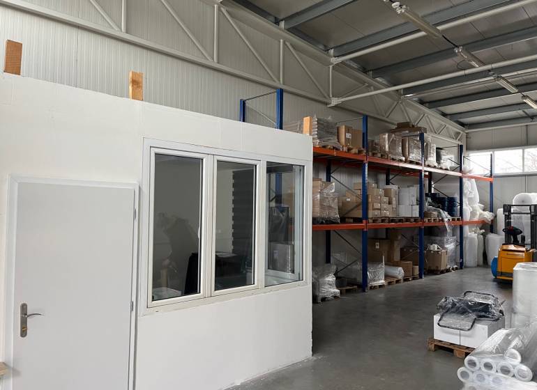 Sklady a haly s regály, zbožím a vysokozdvižným vozíkem.