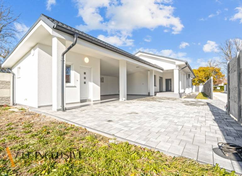 Rodinný dům v Orechové Potôni s bílou fasádou a dlážděným vstupem.