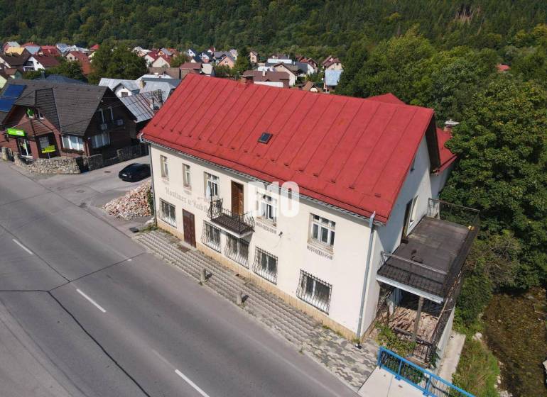 Budova v Belej s červenou střechou, okolní domy a příroda.