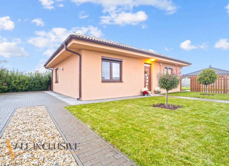 Rodinný dům v Gabčíkovu obklopený zelení, dlažbou a malým stromkem v zahradě.