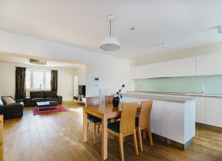 Kuchyň a obývací pokoj v rodinném domě s podlahou s dřevěným dekorem a světlým nábytkem.