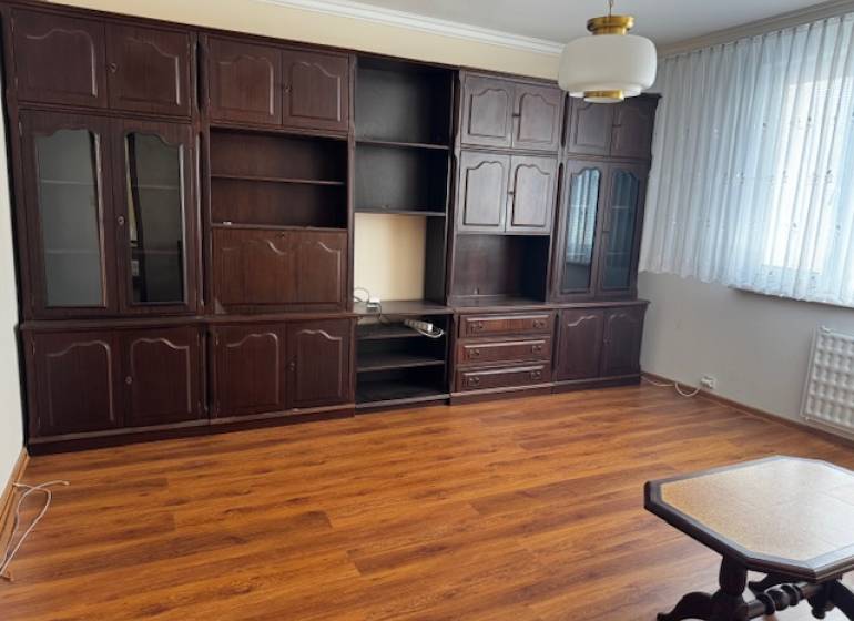 Obývací pokoj v 3-pokojovém bytě s podlahou s dřevěným dekorem, tmavý nábytek.