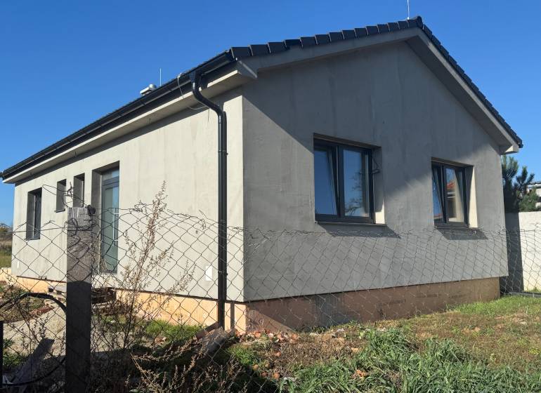 Rodinný dům v Tesárskych Mlyňanoch s šedou fasádou a okny, oplocený plotovým pletivem.