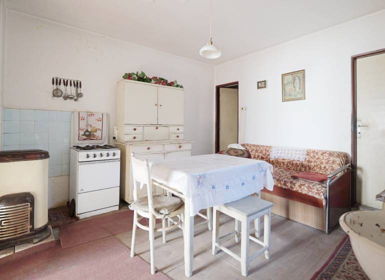 Jídelna s plynovým sporákem, stolem a pohovkou v rodinném domě, podlaha s dřevěným dekorem.