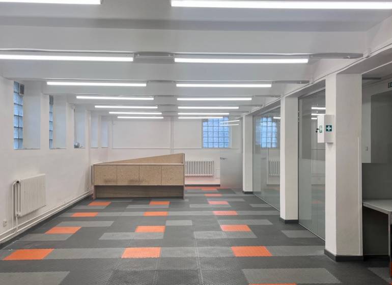 Obchodní prostory s barevnou podlahou a prosklenými příčkami, vhodné pro kanceláře nebo provozovnu.