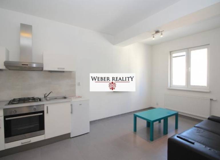 Kuchyně v 2-pokojovém bytě s šedou podlahou, kuchyňskou linkou a posezením.