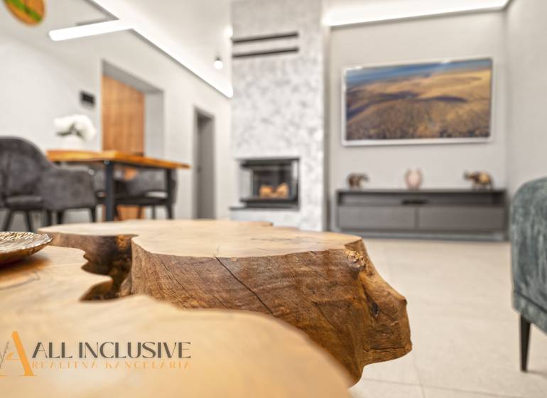 Obývací pokoj v rodinném domě s krbem, dekorativním dřevěným stolem a pohodlným sezením.