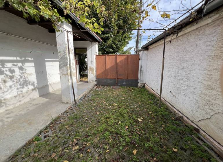 Dvůr rodinného domu v Jablonci s kamennou dlažbou a zelení.