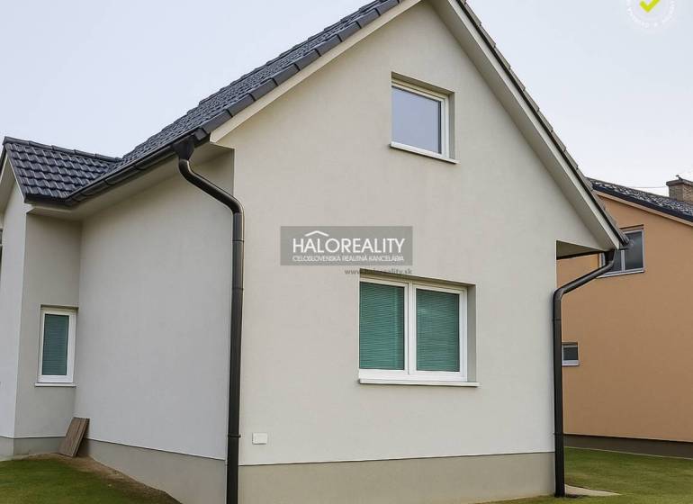 Rodinný dům v Kľačne s bílou fasádou a šikmou střechou na udržovaném trávníku.