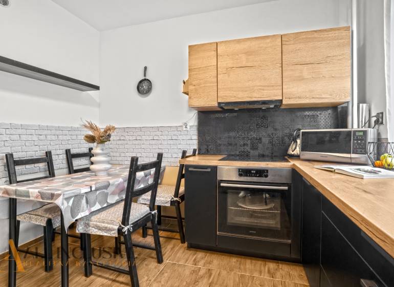 Kuchyně s dřevěným dekorem, jídelním stolem a spotřebiči ve 3pokojovém bytě.