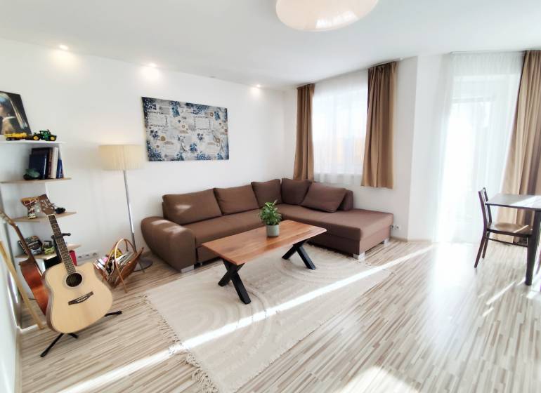 Obývací pokoj v rodinném domě s velkou sedačkou a podlahou s dřevěným dekorem.