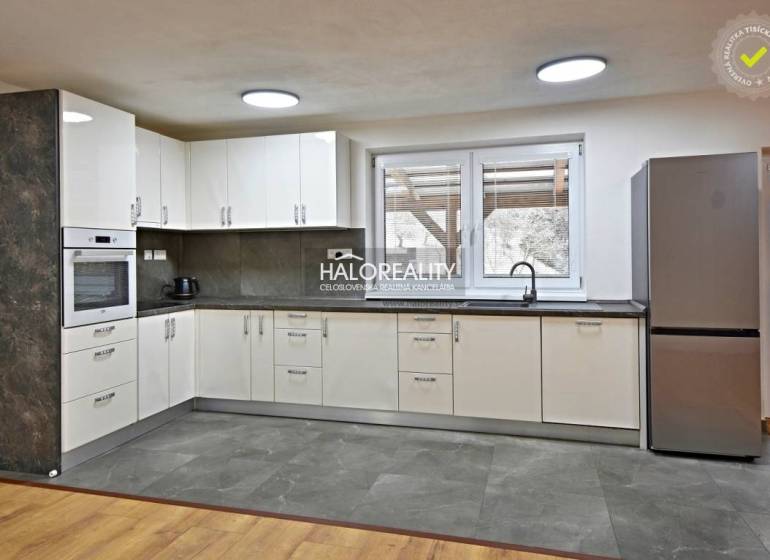 Kuchyně v rodinném domě s moderními spotřebiči a podlahou s dřevěným dekorem.