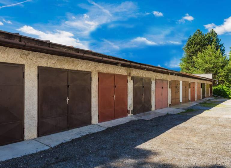 Řada za řadou, na Pálovické cestě, stojí garáže s plechovými dveřmi.