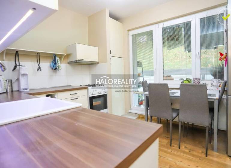 Kuchyně v 2-pokojovém bytě s podlahou s dřevěným dekorem, jídelním stolem a spotřebiči.
