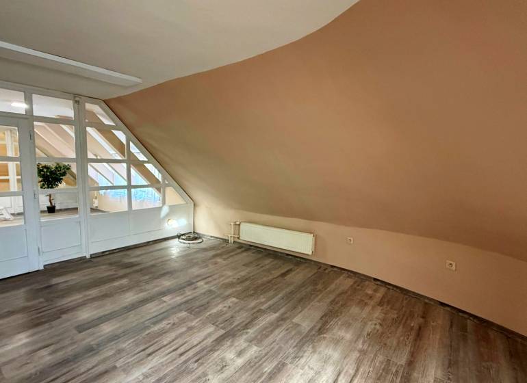 Interiér budovy s podlahou s dřevěným dekorem a šikmou světle hnědou stěnou.