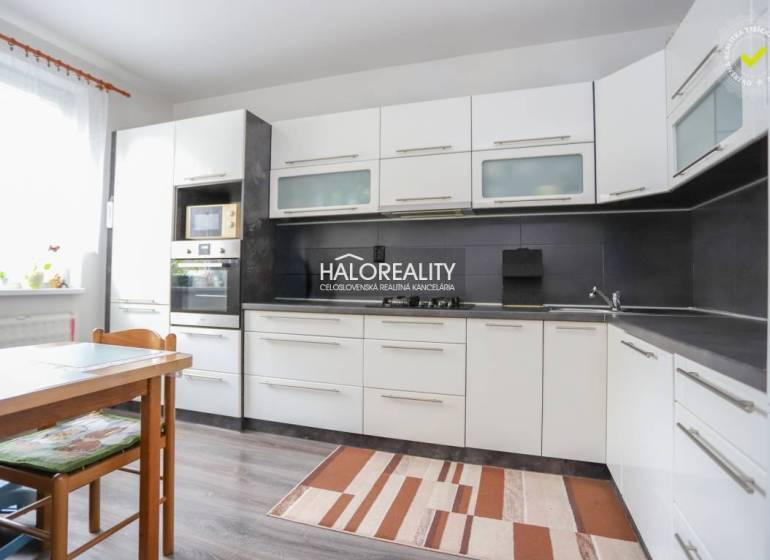 Kuchyně ve 3-pokojovém bytě s bílými skříňkami a podlahou s dřevěným dekorem.