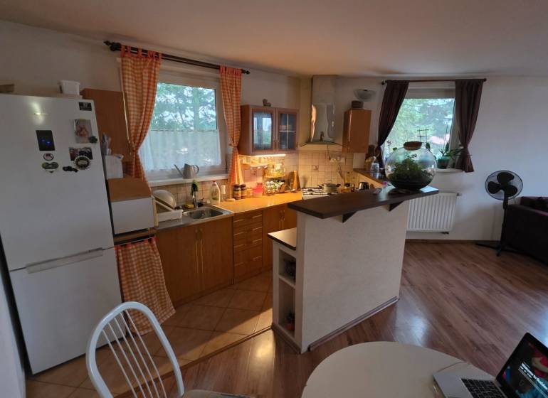 Kuchyně ve 3-pokojovém bytě s podlahou s dřevěným dekorem a jídelním stolem.