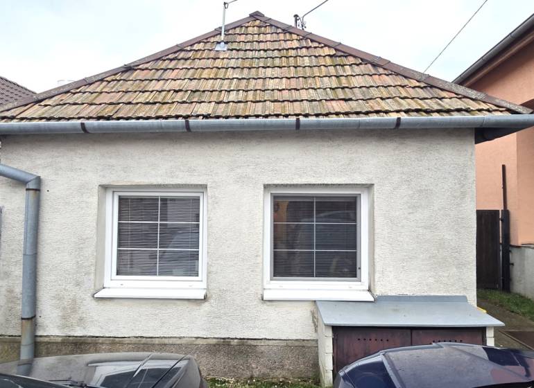 Rodinný dům v Dolních Orešanech s klasickou střechou a dvěma okny v popředí.