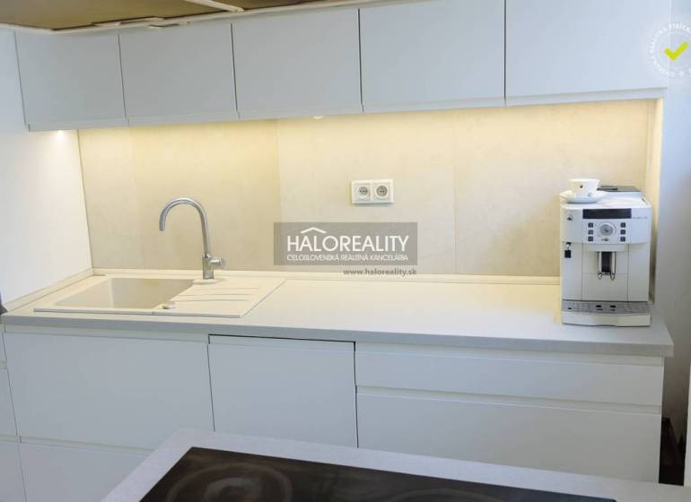 Kuchyně s bílými skříňkami a kávovarem ve 3-pokojovém bytě.
