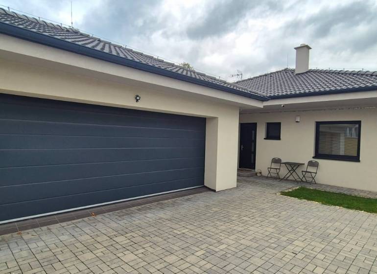 Rodinný dům ve Studience se dvěma židlemi a stolkem na dlážděném dvoře.