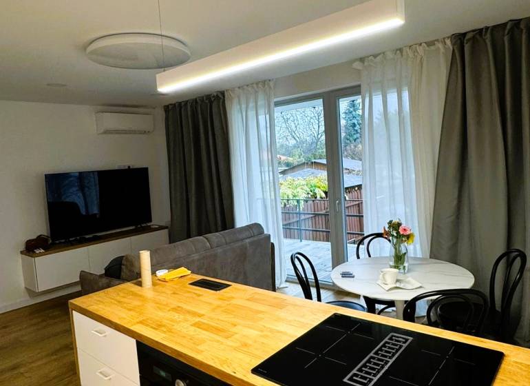 Kuchyňský ostrůvek s varnou deskou, jídelní stůl a pohovka v rodinném domě.