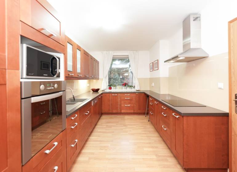 Kuchyně v rodinném domě s dřevěným dekorem, s varnou deskou a mikrovlnnou troubou.