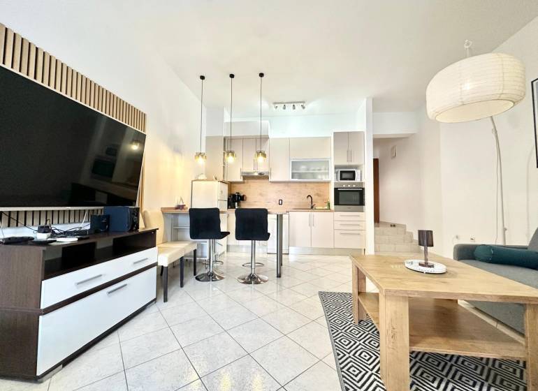 Rekreační apartmán s prostorným obývacím pokojem, kuchyní a televizí.