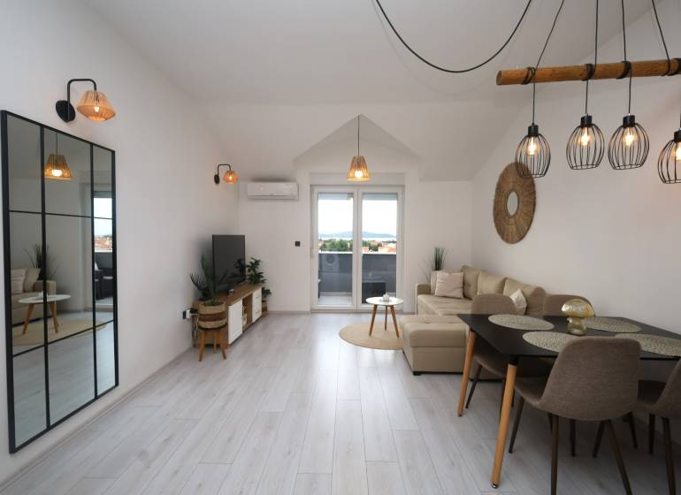 Obývací pokoj v rekreačním apartmánu s podlahou s dřevěným dekorem a velkým zrcadlem.