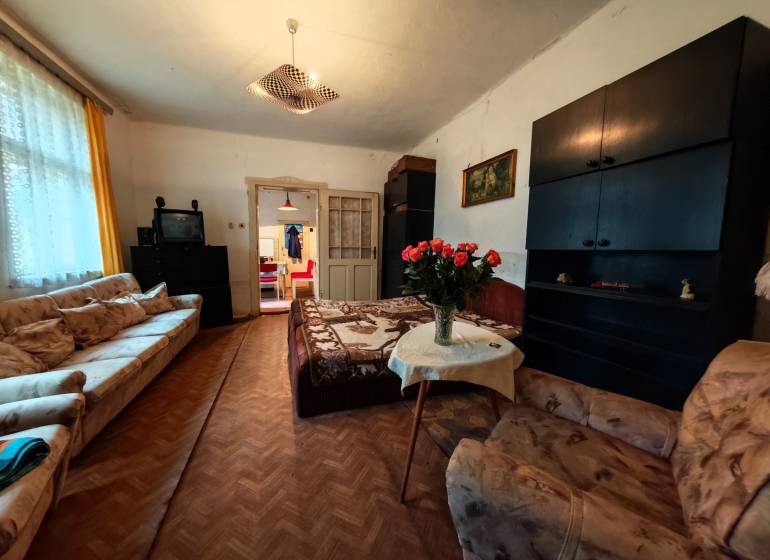 Obývací pokoj v rodinném domě s pohovkami, TV a podlahou s dřevěným dekorem.