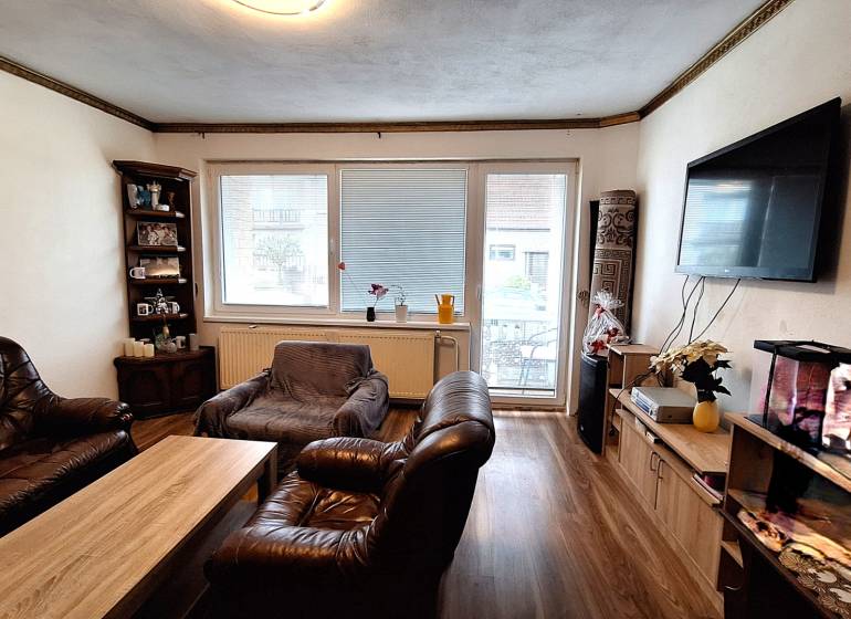 Obývací pokoj v rodinném domě s koženým nábytkem a podlahou s dřevěným dekorem.