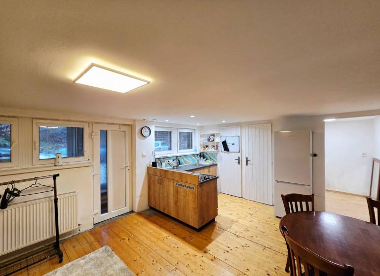 Kuchyňa v 1-pokojovém bytě s podlahou s dřevěným dekorem a stolem.