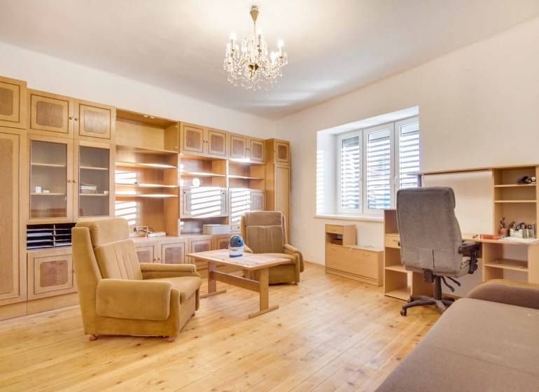 Interiér rodinného domu s nábytkem, podlahou s dřevěným dekorem a lustrem.