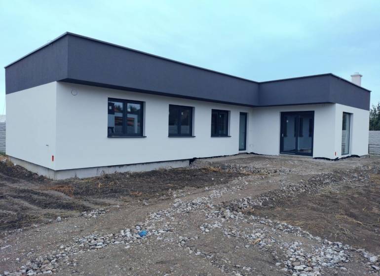 Rodinný dům v Žihárci s plochou střechou a světlou fasádou.