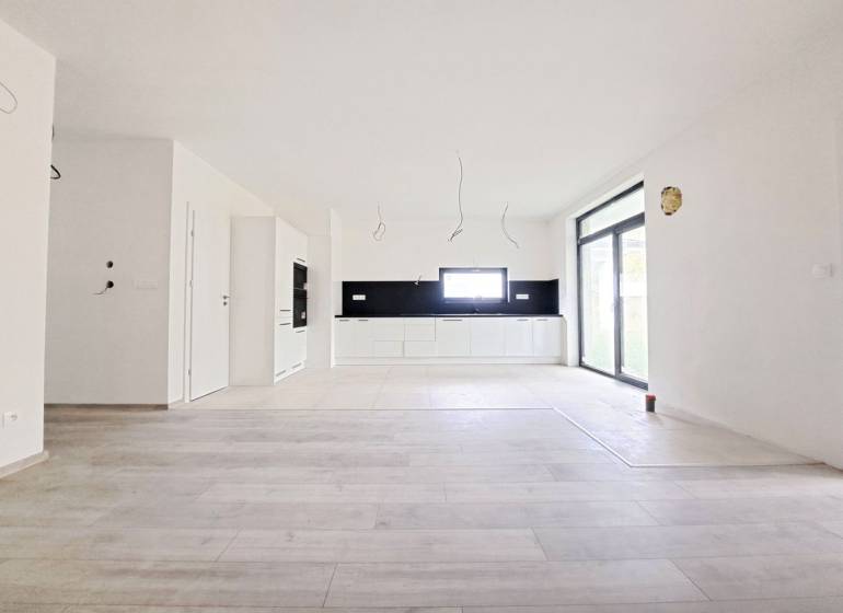 Prostorná kuchyně s černým obkladem a podlahou s dřevěným dekorem v rodinném domě.