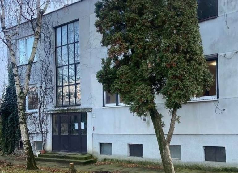 Exteriér budovy v Seliciach, obklopený stromy a travnatým prostředím.