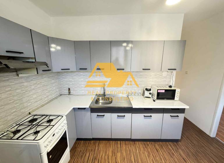 Kuchyně ve 3-pokojovém bytě s podlahou s dřevěným dekorem a moderním vybavením.