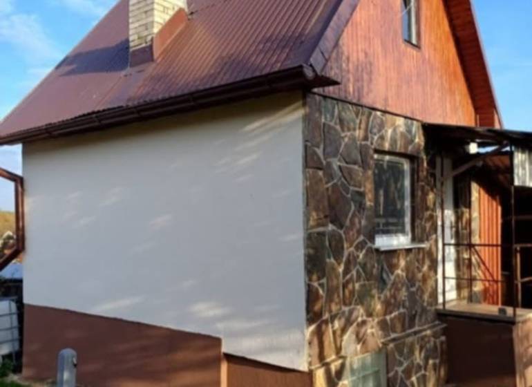 Chata v Pozdišovcích s kamennou fasádou a hnědou plechovou střechou.