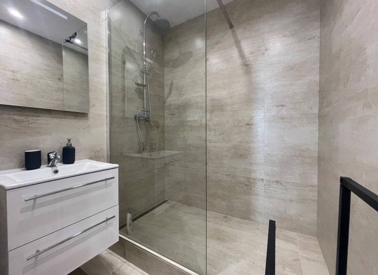 Koupelna ve 3pokojovém bytě se sprchovým koutem a úložným prostorem pod umyvadlem.