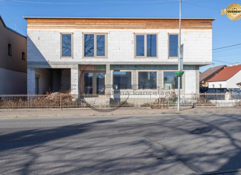 Budova ve Velkých Levárech s nedokončenou fasádou stojící u cesty.