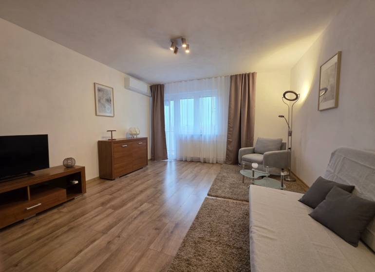 Obývací pokoj v 3-pokojovém bytě s podlahou s dřevěným dekorem a pohodlným nábytkem.