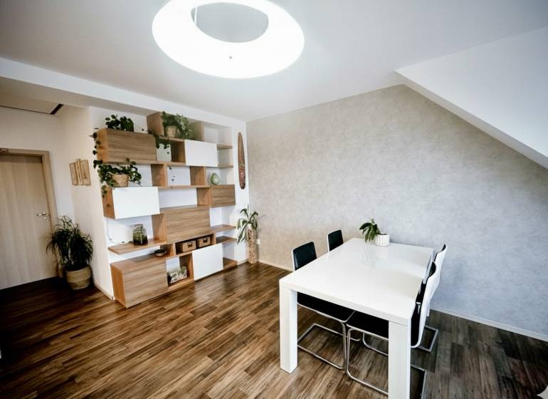 Jídelní stůl, židle a police s dekoračními prvky v 3-pokojovém bytě s podlahou s dřevěným dekorem.