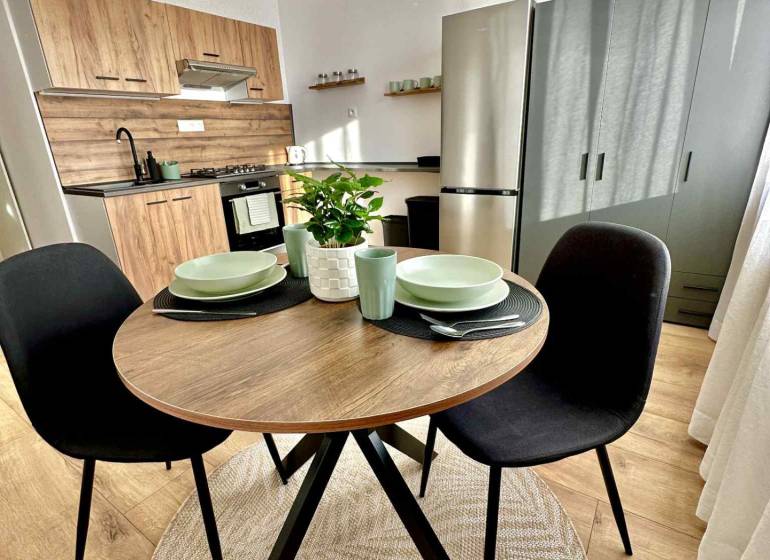 Kuchyňský kout v 1-pokojovém bytě s dřevěným dekorem a kruhovým stolem.