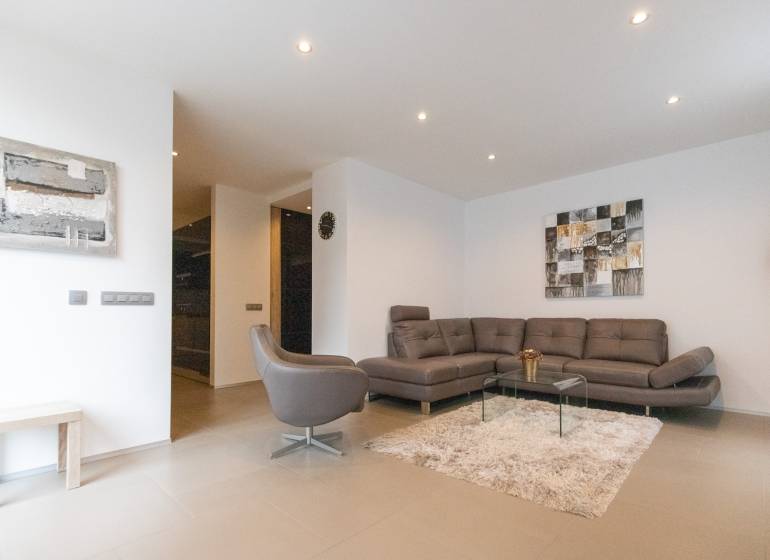 Obývací pokoj v 2pokojovém bytě s pohovkou, křeslem, kobercem a obrazy na stěně.