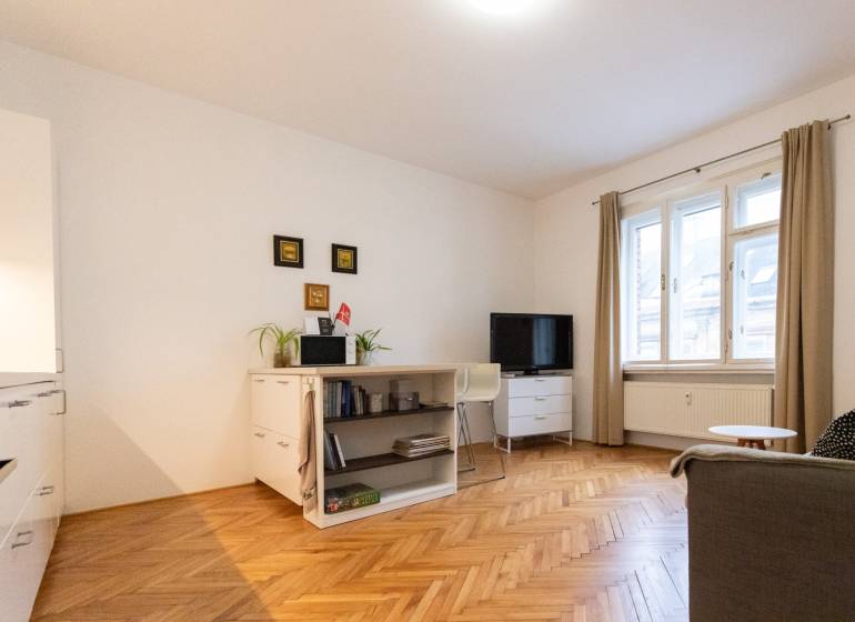 Obývací pokoj v 2pokojovém bytě se světlým nábytkem a podlahou s dřevěným dekorem.