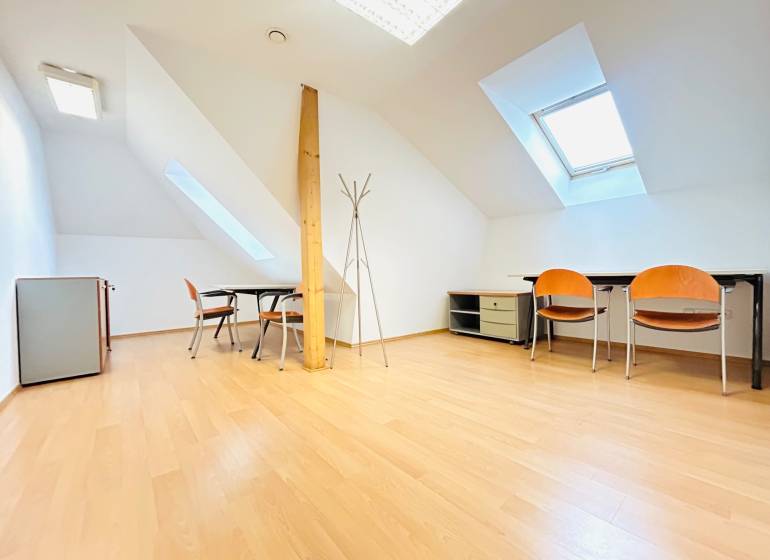 Kanceláře s podlahou s dřevěným dekorem, podkrovní okna, stoly a židle.