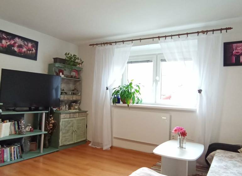 Obývací pokoj v rodinném domě s dřevěným dekorem podlahy a květinovými dekoracemi.