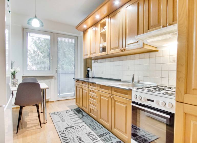 Kuchyně ve 4pokojovém bytě s podlahou s dřevěným dekorem a jídelním stolem.