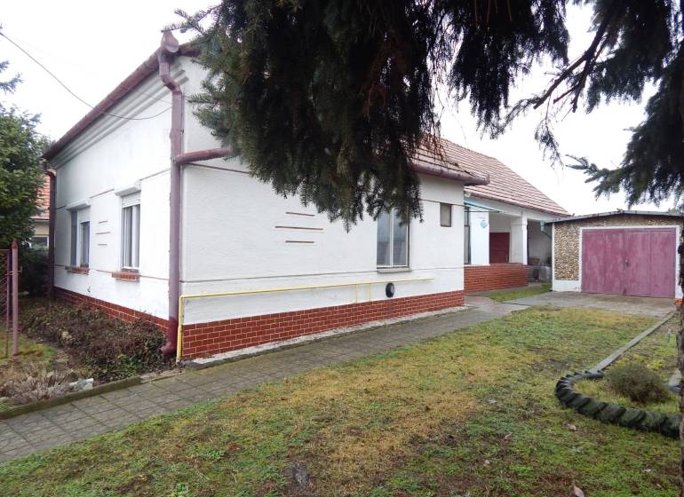 Rodinný dům v Kravanoch nad Dunajem s garáží, vedle chodník a travnatá plocha.