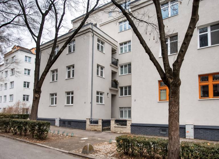 Bytový dům v Bratislavě na Jurajově dvoře, U staré prachárny. Čtyřpatrová budova, stromy, chodník.