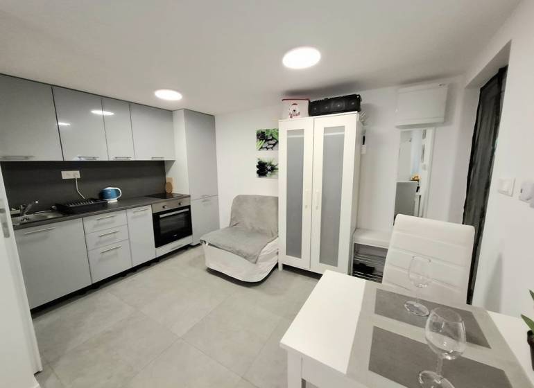 Kuchyně v chatě, s jídelním stolem a šedými kuchyňskými skříňkami.